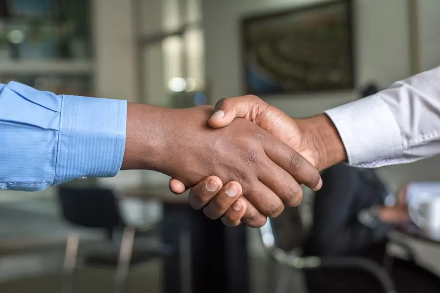 Two people shaking hands in an office, representing an honest, no-fee partnership