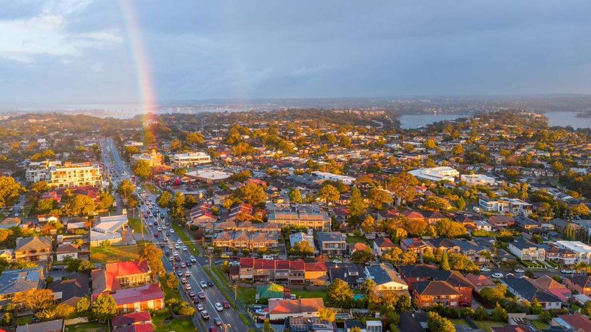 Aerial view of an Australian suburb with houses and a rainbow at sunset