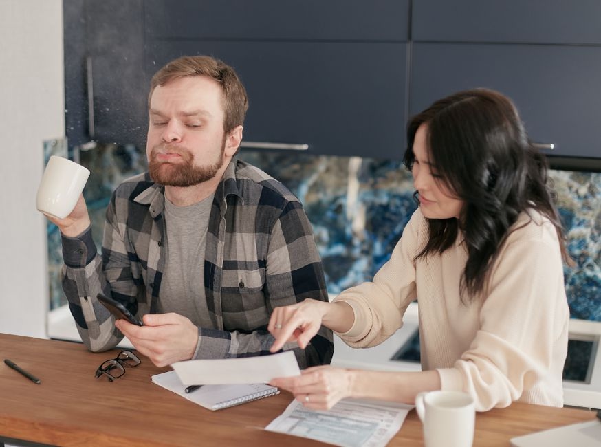Australian couple reviewing household bills and statements at a kitchen table