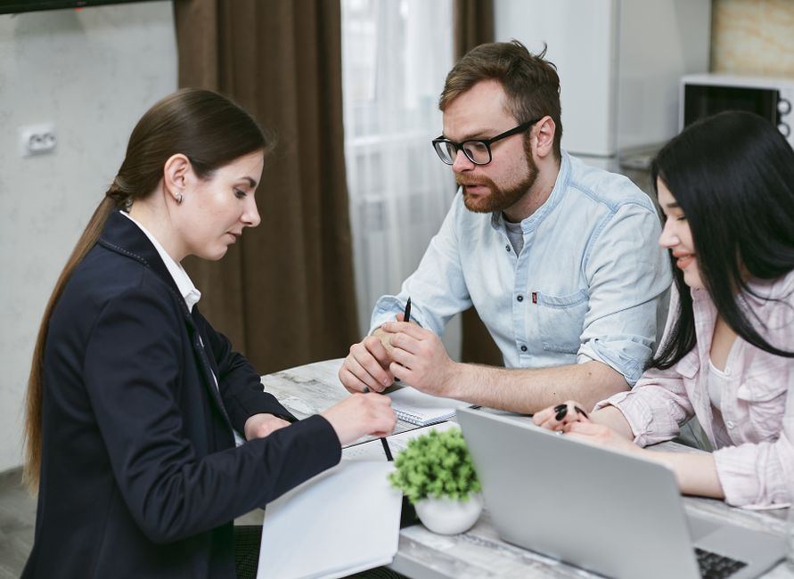 Couple discussing a home loan application with an adviser at a desk