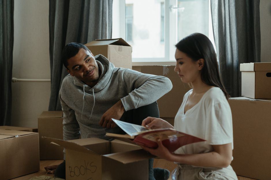 Couple unpacking boxes in a new home and looking through a photo album