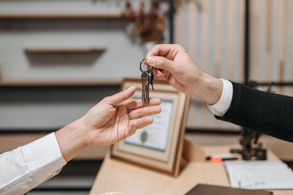 Hands passing house keys across a desk at a property settlement