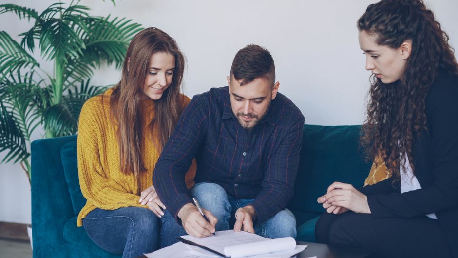 Couple reviewing loan documents with an adviser at a table