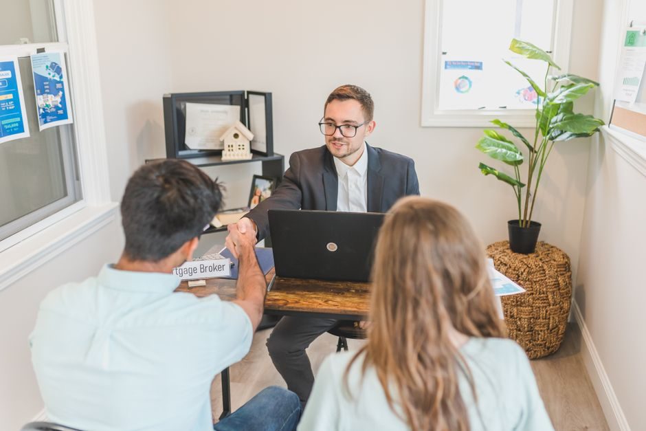 Mortgage broker going through loan documents with a client at a desk